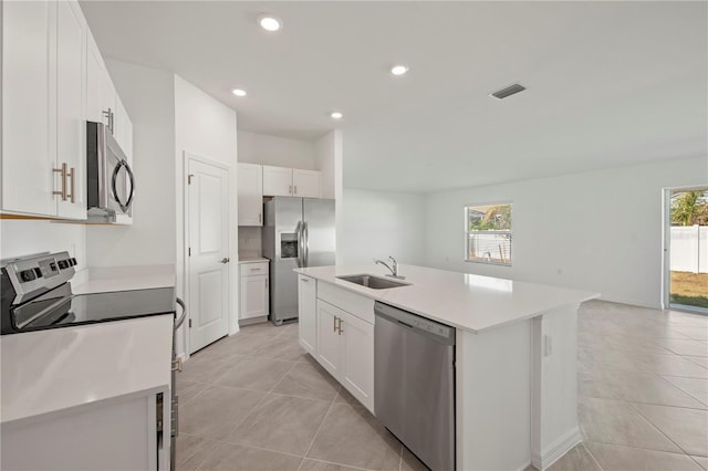 kitchen with stainless steel appliances, a kitchen island with sink, sink, white cabinets, and light tile patterned flooring