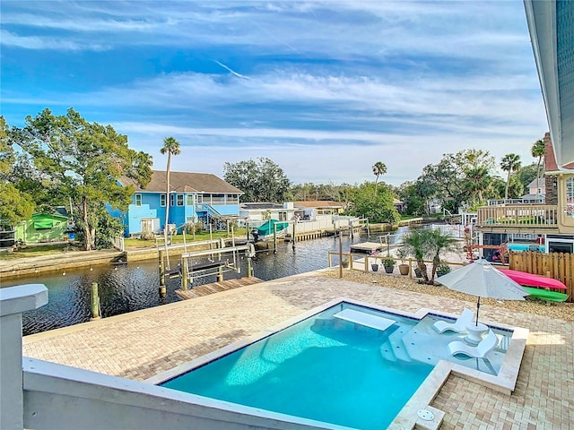 view of pool with a boat dock, a patio, and a water view