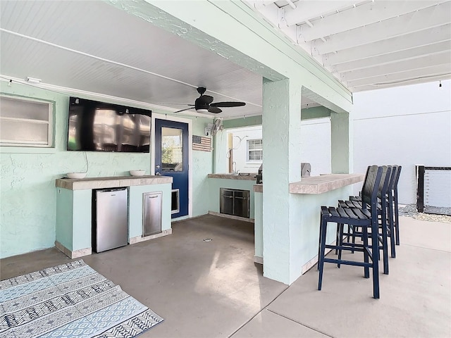 view of patio / terrace with area for grilling, ceiling fan, and a bar