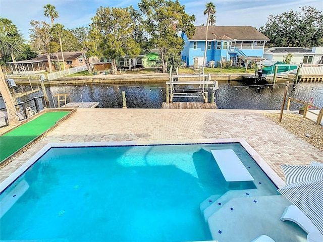 view of swimming pool featuring a patio, a water view, and a dock