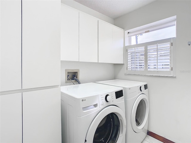 washroom featuring cabinets, a textured ceiling, and washing machine and clothes dryer