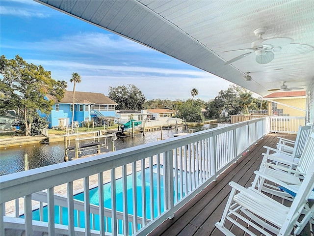 view of swimming pool with a water view, a dock, and ceiling fan