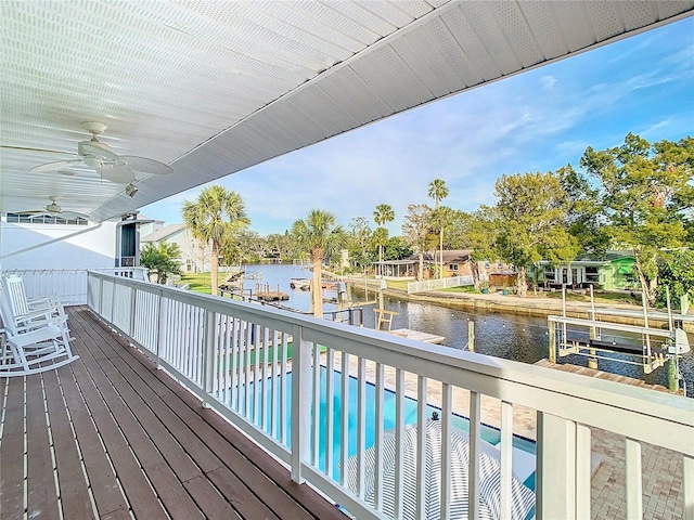 exterior space with ceiling fan, a water view, and a dock