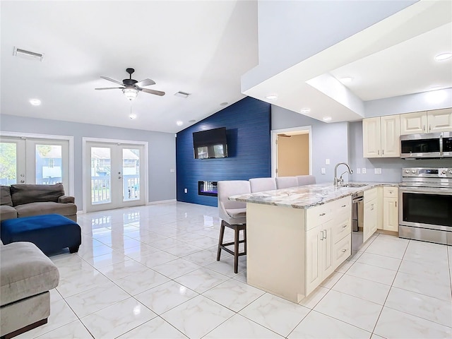 kitchen featuring lofted ceiling, french doors, a kitchen breakfast bar, appliances with stainless steel finishes, and kitchen peninsula