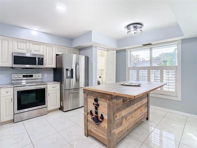 kitchen featuring white cabinets, light tile patterned floors, independent washer and dryer, and appliances with stainless steel finishes