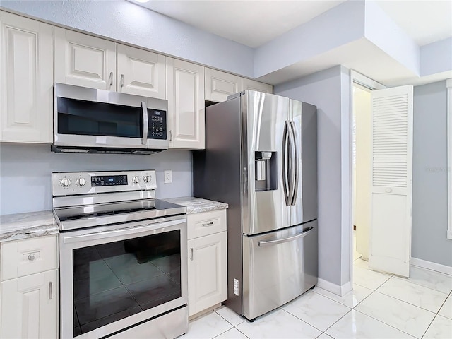 kitchen with white cabinetry, stainless steel appliances, and light tile patterned floors