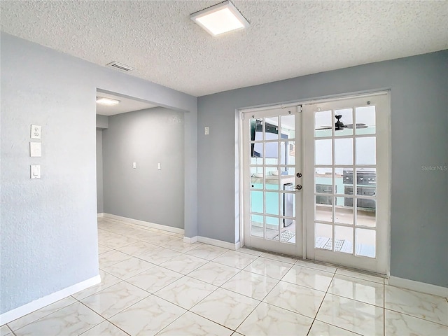 unfurnished room featuring ceiling fan, a textured ceiling, and french doors