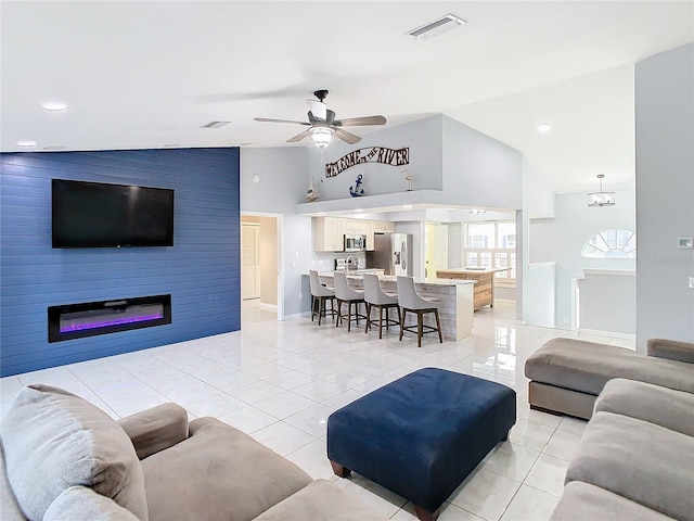 living room featuring ceiling fan, a large fireplace, light tile patterned flooring, and high vaulted ceiling