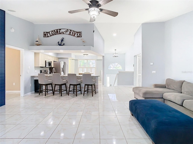 tiled living room with ceiling fan with notable chandelier