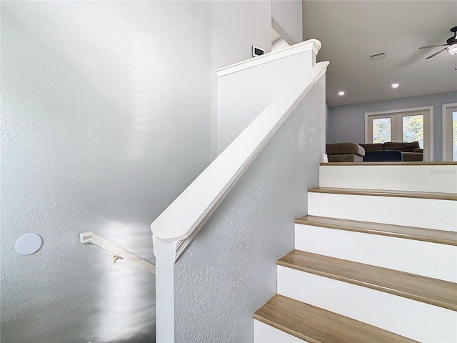 stairway featuring ceiling fan