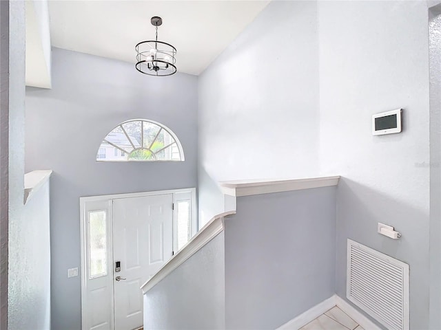 tiled entryway with a high ceiling and an inviting chandelier