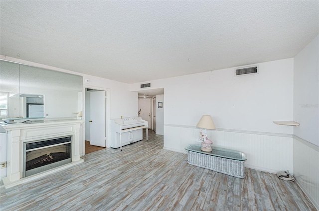 unfurnished living room with light wood-type flooring and a textured ceiling