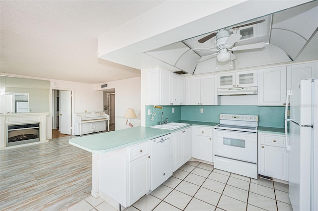 kitchen featuring white cabinets, sink, white appliances, and kitchen peninsula