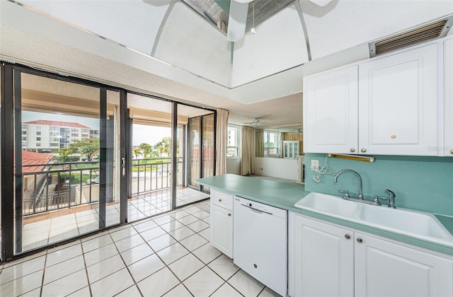 kitchen featuring dishwasher, sink, ceiling fan, light tile patterned floors, and white cabinetry