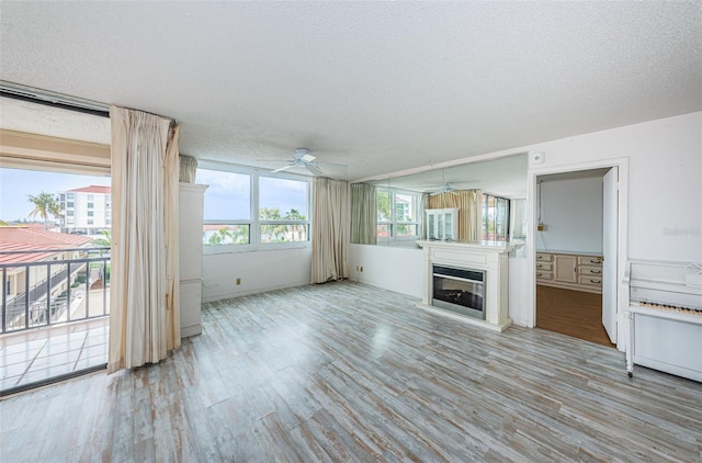 unfurnished living room featuring light wood-type flooring, a textured ceiling, and ceiling fan