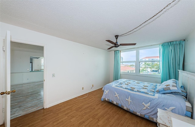 bedroom featuring wood-type flooring, a textured ceiling, and ceiling fan