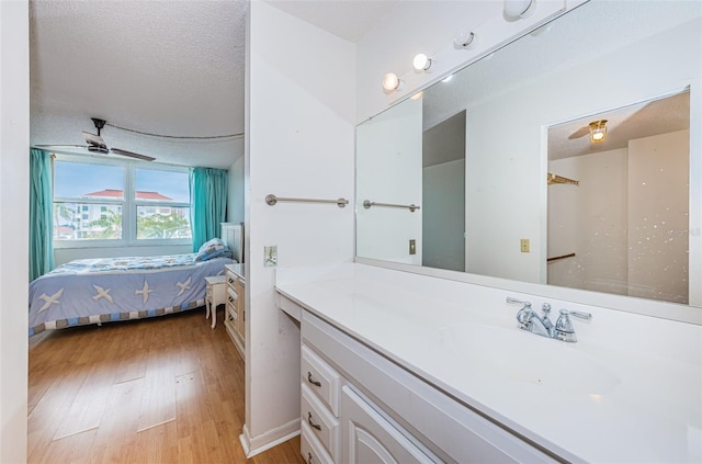 bathroom with ceiling fan, wood-type flooring, a textured ceiling, and vanity