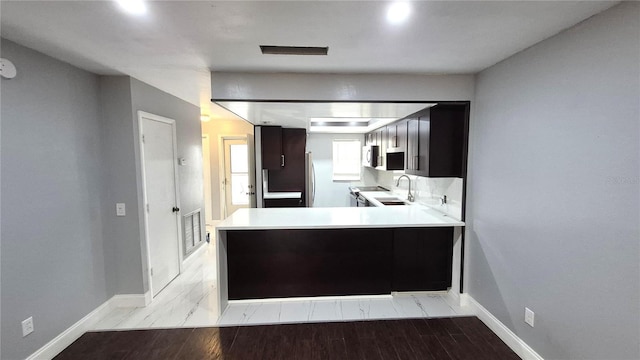 kitchen with kitchen peninsula, sink, and light wood-type flooring