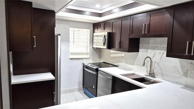 kitchen with light stone countertops, appliances with stainless steel finishes, backsplash, dark brown cabinetry, and sink