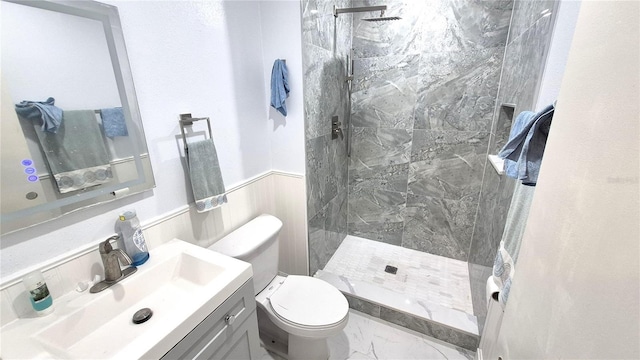 bathroom with vanity, toilet, and tiled shower