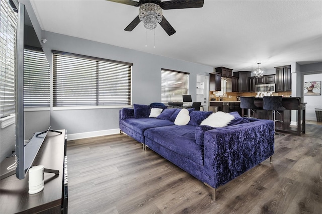 living room with ceiling fan with notable chandelier, dark hardwood / wood-style floors, and sink