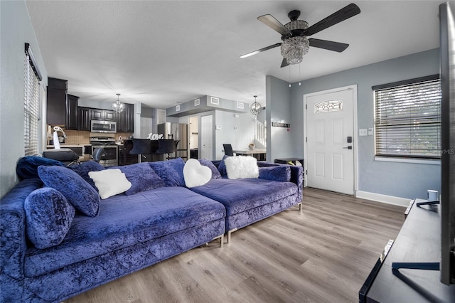 living room featuring light hardwood / wood-style floors and ceiling fan with notable chandelier