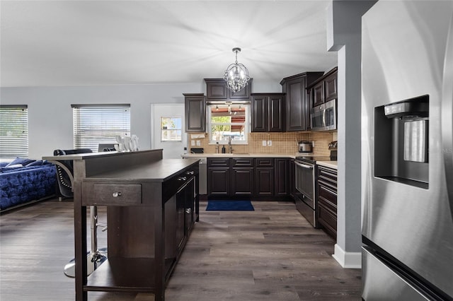 kitchen featuring decorative light fixtures, tasteful backsplash, sink, appliances with stainless steel finishes, and dark wood-type flooring