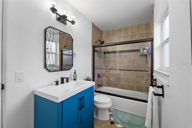 full bathroom with tile patterned floors, shower / bath combination with glass door, vanity, and toilet