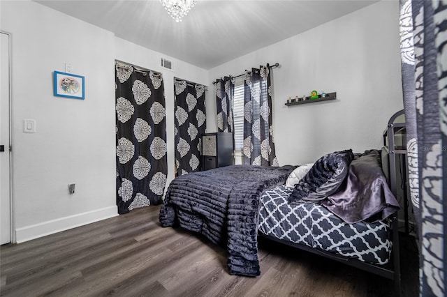 bedroom with hardwood / wood-style flooring and a notable chandelier