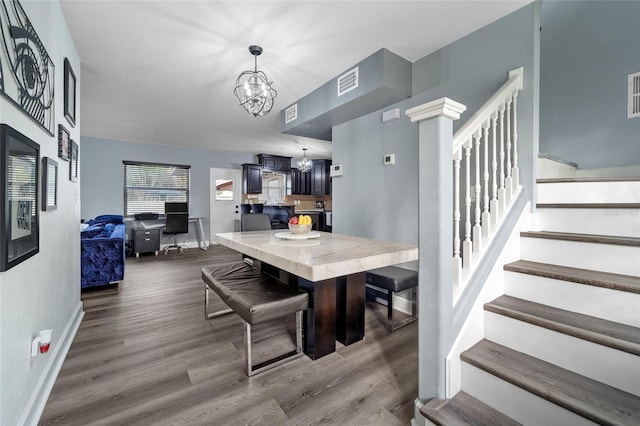 dining space featuring dark wood-type flooring and a notable chandelier