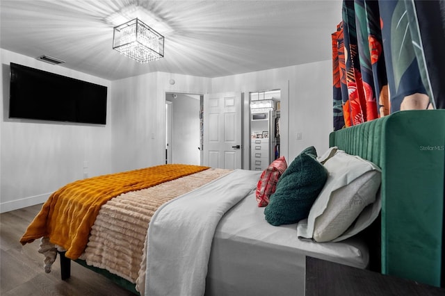 bedroom with an inviting chandelier and hardwood / wood-style floors