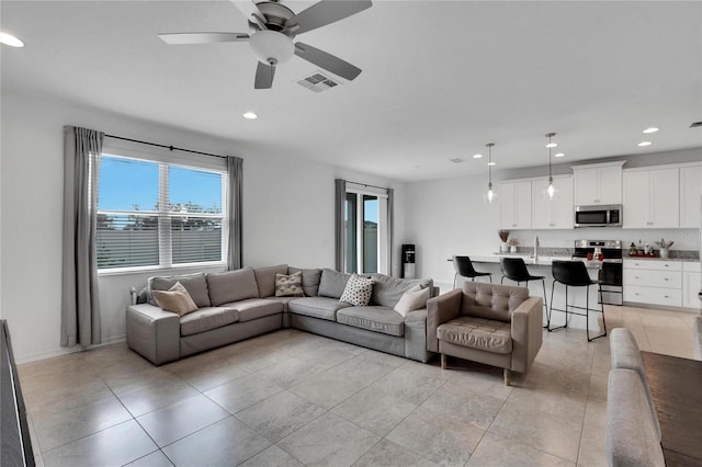 living room featuring ceiling fan, light tile patterned flooring, and a wealth of natural light