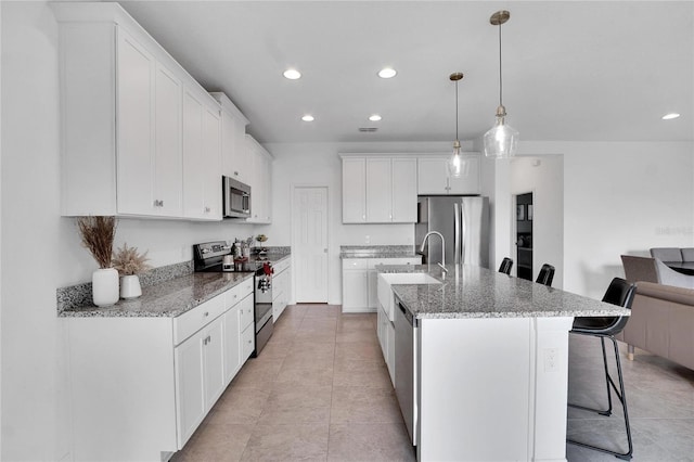 kitchen featuring a breakfast bar, sink, decorative light fixtures, white cabinetry, and stainless steel appliances