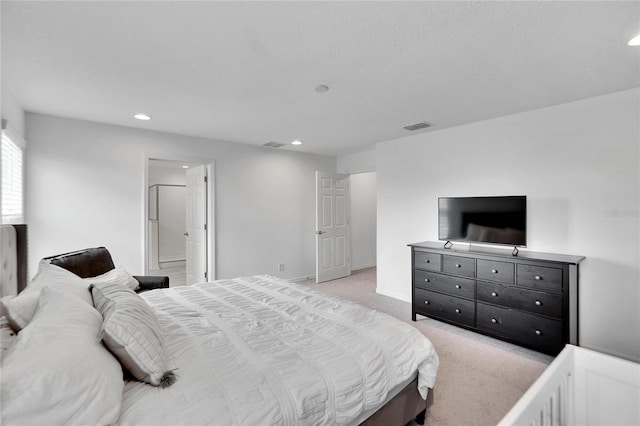 bedroom with connected bathroom and light colored carpet