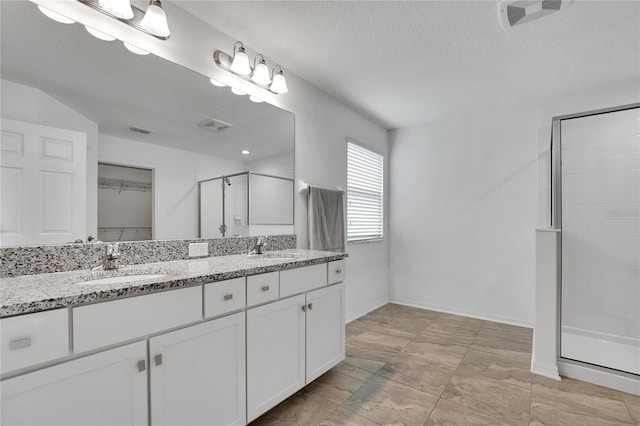 bathroom with vanity, a shower with shower door, and a textured ceiling