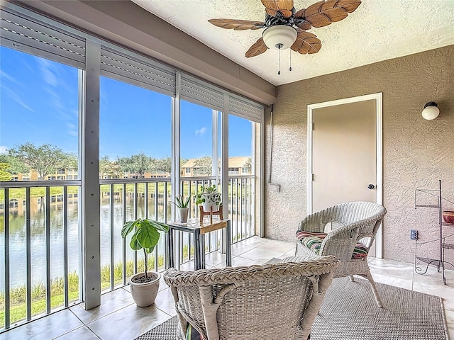 sunroom / solarium featuring ceiling fan and a water view