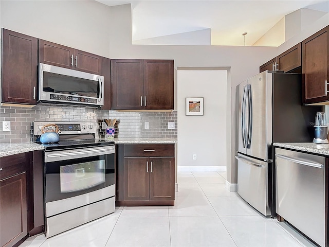 kitchen featuring backsplash, appliances with stainless steel finishes, light tile patterned flooring, light stone counters, and dark brown cabinetry