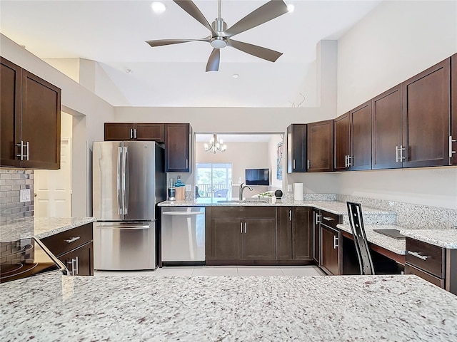 kitchen with ceiling fan with notable chandelier, sink, vaulted ceiling, light stone countertops, and appliances with stainless steel finishes