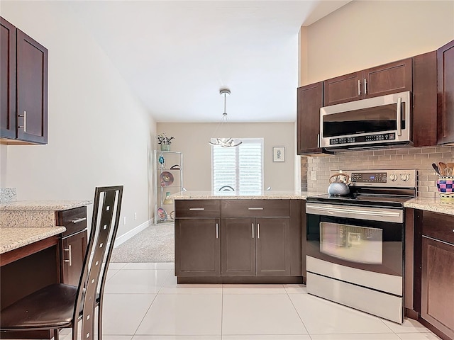 kitchen featuring light carpet, appliances with stainless steel finishes, light stone counters, dark brown cabinetry, and hanging light fixtures