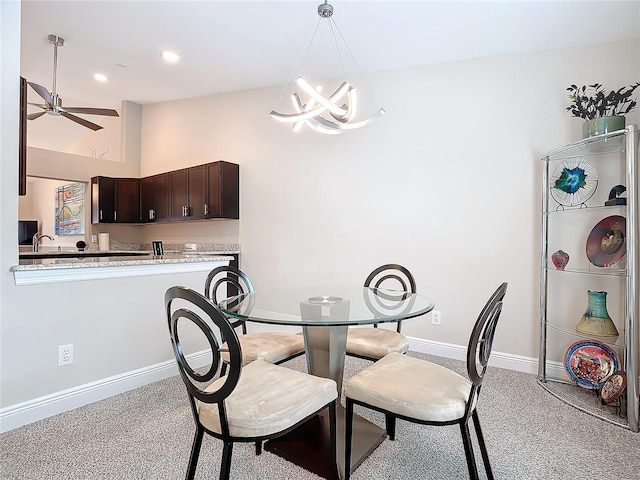 carpeted dining area featuring sink and ceiling fan with notable chandelier