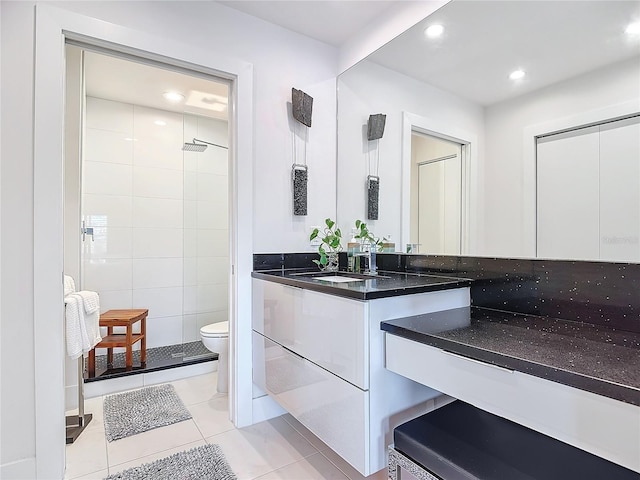 bathroom with toilet, vanity, tile patterned floors, and walk in shower