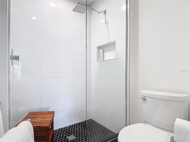 bathroom featuring a tile shower and toilet