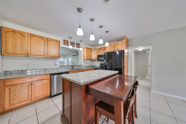 kitchen featuring a center island, black appliances, pendant lighting, sink, and light stone countertops