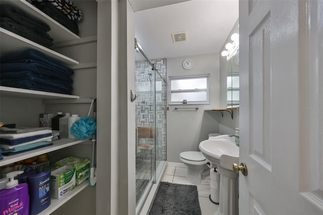 bathroom featuring tile patterned floors, a shower with door, and toilet