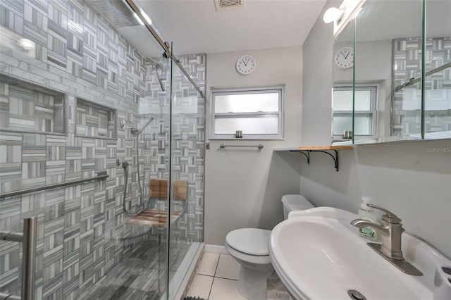 bathroom featuring toilet, tile patterned flooring, a shower with door, and sink