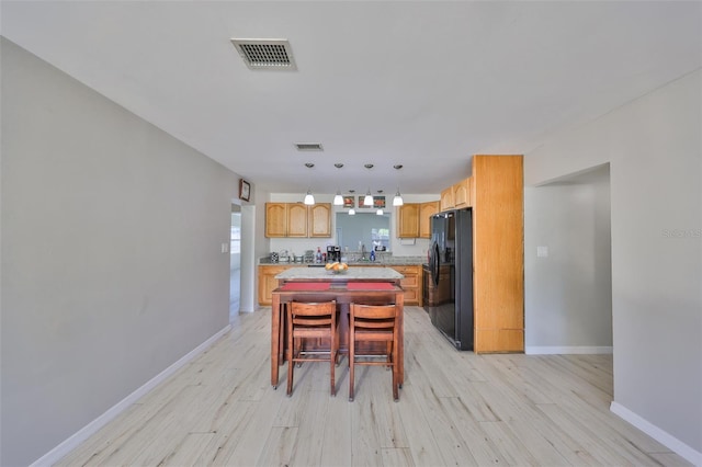 kitchen with visible vents, light wood-style floors, a center island, and freestanding refrigerator