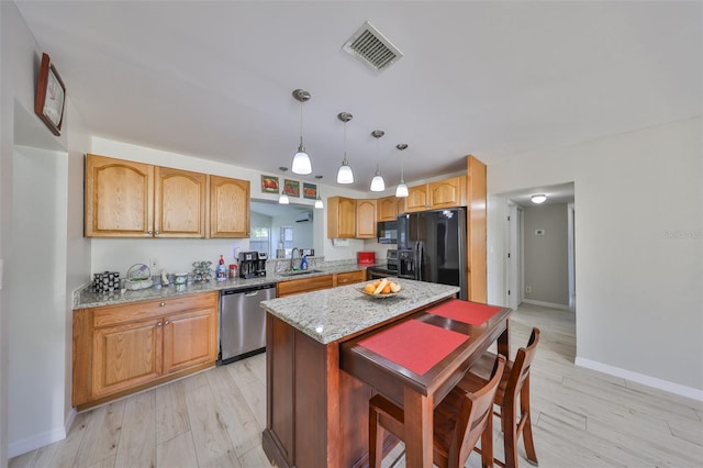 kitchen featuring light stone countertops, black appliances, a center island, a sink, and visible vents
