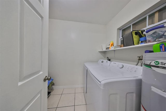 clothes washing area featuring light tile patterned floors, washing machine and dryer, baseboards, water heater, and laundry area