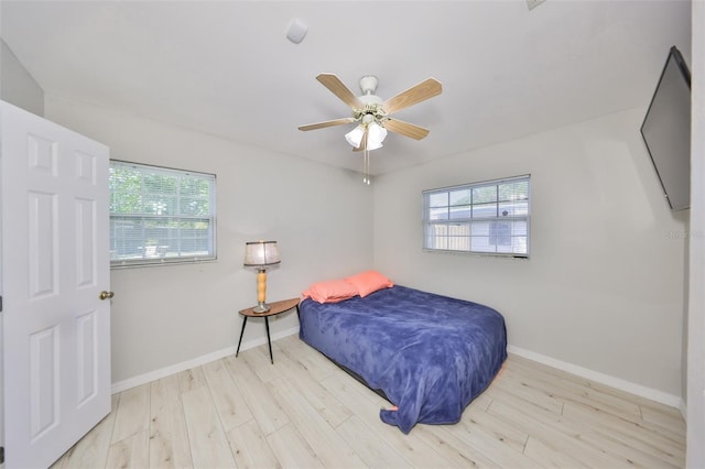 bedroom featuring wood finished floors, baseboards, and multiple windows