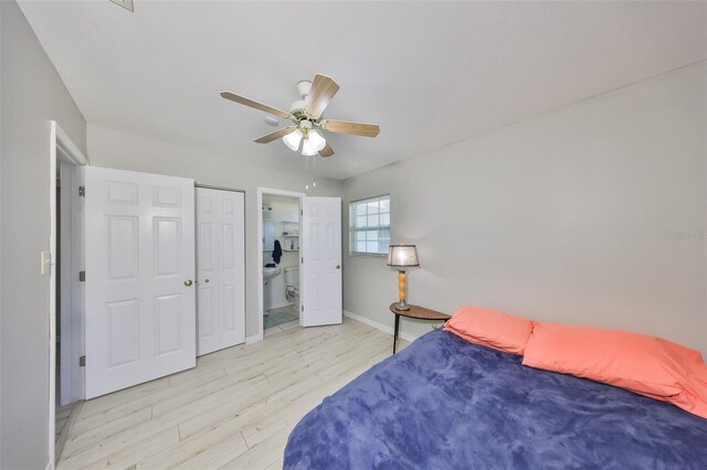 bedroom featuring wood finished floors, ensuite bathroom, a ceiling fan, and baseboards